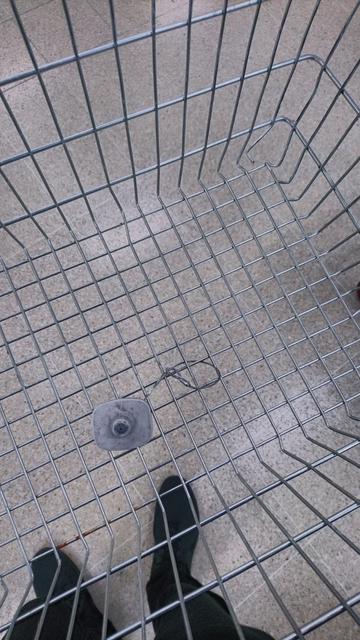 a downwards view into a wire shopping basket showing an attached security tag