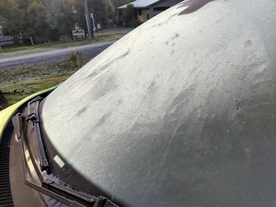 A car windscreen covered in a layer of thin ice.