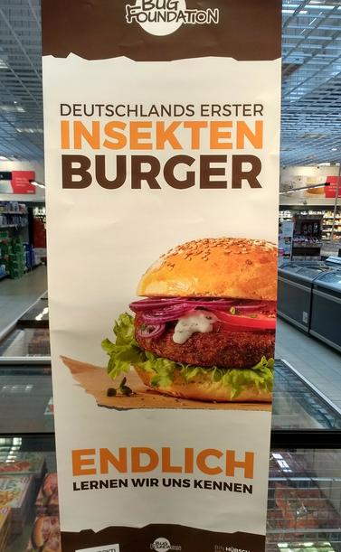 Großer Werbeaufsteller für "Deutschlands erster Insektenburger", sieht eigentlich sehr lecker aus.