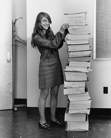margaret hamilton standing next to stack of computer code, 1960s