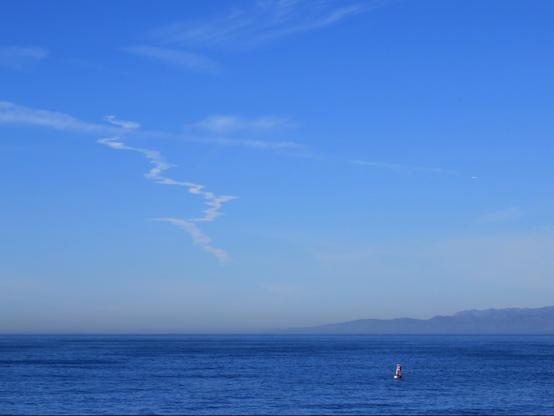 Wavy smoke/vapor trail from a rocket launch above the ocean.