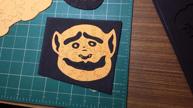 A picture of a goblin-looking face cut into puzzle pieces and put together using black and orange mixed together.