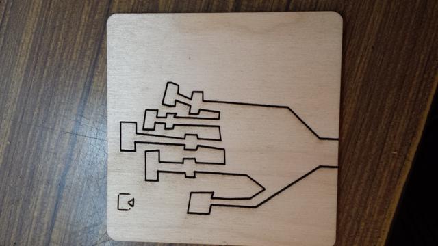 A flat blocky hand cut into a piece of wood. The hand is still inside the wood it was cut from.