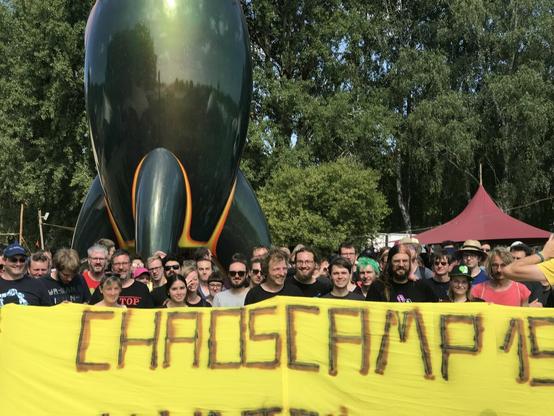 Menschen mit Transpi "Chaoscamp 19" vor der CCC-Rakete, Nahaufnahme