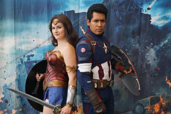 Cosplayers dressed as Wonder Woman and Captain America against that damaged city backdrop.