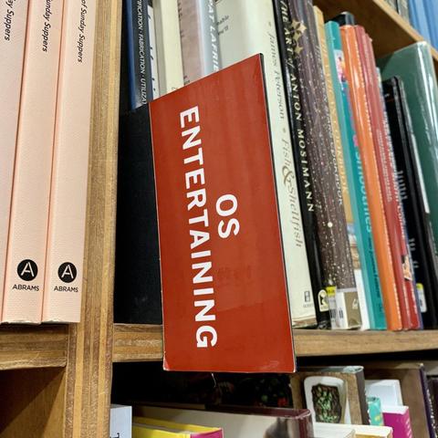 A shelf of books in a bookstore is categorized and labeled as “OS Entertaining"