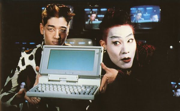 Razor and Blade from the movie Hackers holding an old laptop, probably RISC architechture.