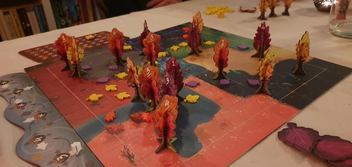 A boardgame called BOSK. There are paper trees placed on a board and wodden leaves of different colours strewn about.