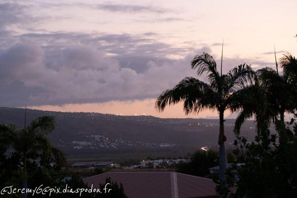Vue paysage couché de soleil, couleurs du ciel légeremment mauve avec trois cocotiers sur la droite