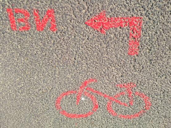 Ein roter Pfeil und Fahrradsymbol auf den Asphalt gesprüht.