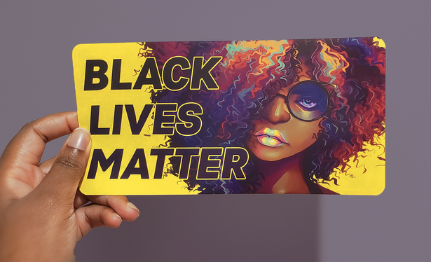 a black hand holding a beautiful neon sticker of a black femme's face and hair, with the text BLACK LIVES MATTER