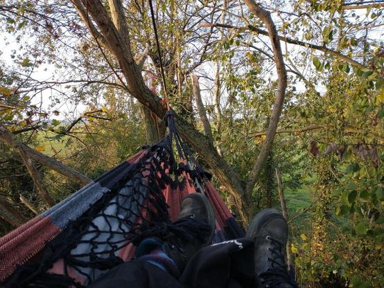 Bild aus einer Hängematte in den Bäumen, Füße in Wanderstiefeln sind zu erkennen