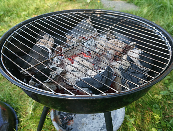 A barbecue grill with charcoal glowing underneath its grate.