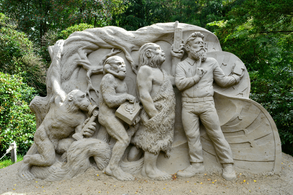 A sand sculpture showing the evolution of humankind in four stages. Each species holds a different  phone with the last one, the modern human, holding a smart phone.