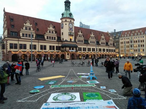Ein großer Eiffelturm ist auf dem Fußboden mit Klebeband abgeklebt, im Hintergrund das Alte Rathaus von Leipzig.