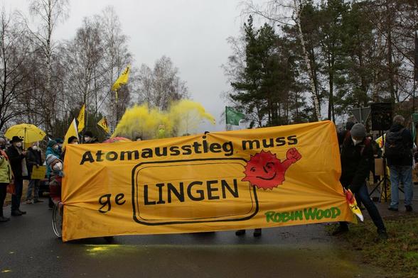 Banner von RobinWood  "Atomausstieg muss geLINGEN  mit antiatom Sonne. In der Luft ist gelbes pulver