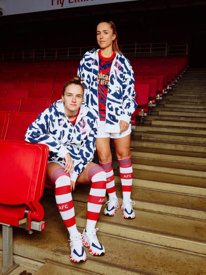 Two professional Arsenal players wearing white and blue hoodies