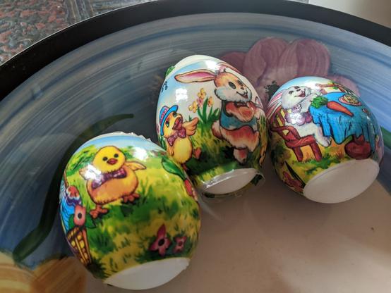 Same three eggs, but turned around a bit.
First one shows a yellow chick with a pink bowtie, and a basket full of decorated eggs.
Second has a chick with a blue and pink hat, and a snazzy pink bowtie, chasing after another Easter Bunny in a stylish blue vest. How exquisite (eggs quisite?).
The third has a bunny sitting at a table, with a carrot in front of them.