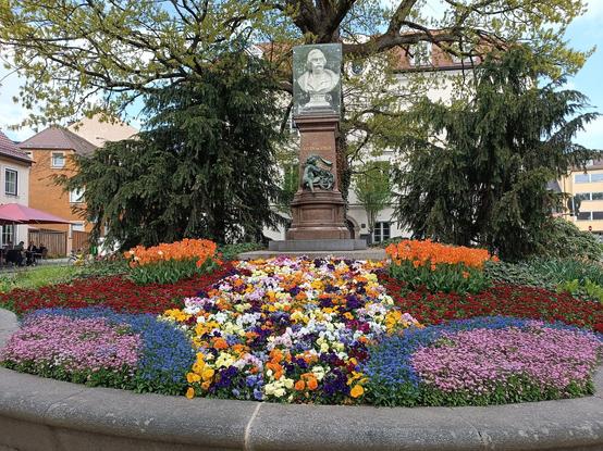 Blumenbeet vor einer Büste