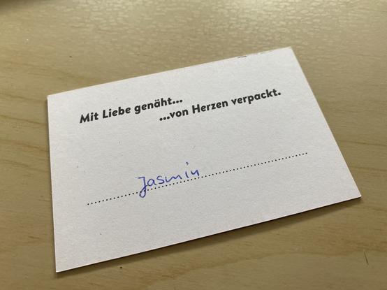 Visitenkarte mit dem Aufdruck „Mit Liebe genäht… … von Herzrn verpackt. Darunter mit Hamd geschrieben: Jasmin