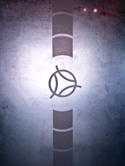 Ein Symbol oder Logo in der Mitte. Pfeilartige halbrunde Blöcke in einer Linie angeordnet befinden sich darüber und darunter.