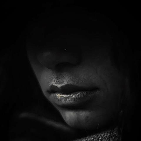 !B

The black and white picture shows a close-up of a woman's mouth, the rest of the face disappears into the shadows.