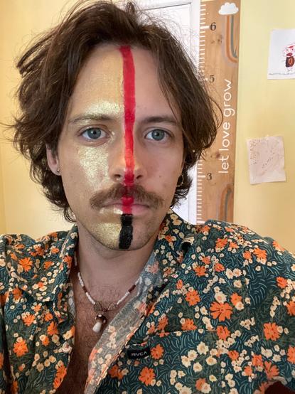 a photo of the author with red, gold, and black face paint
