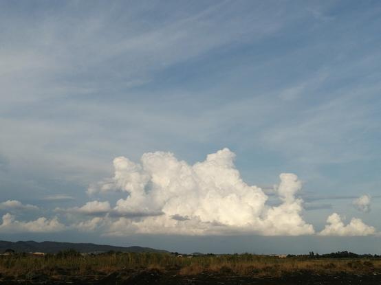 Nuvole blanche con cielo azzurro sullo sfondo sabbie nere e campi.