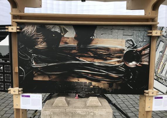An image in an exhibition. Dark photograph showing thick strings of cables on a table