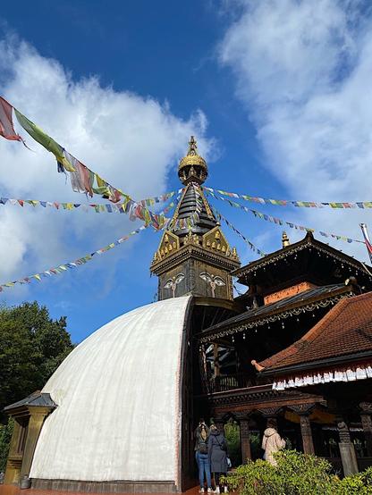 zwei halbe Tempel unterschiedlicher Religionen sind direkt aneinander gebaut. 
Links eine weiße Kuppel mit Türmchen drauf und rechts Säulenhalle um ein Wasserbecken
