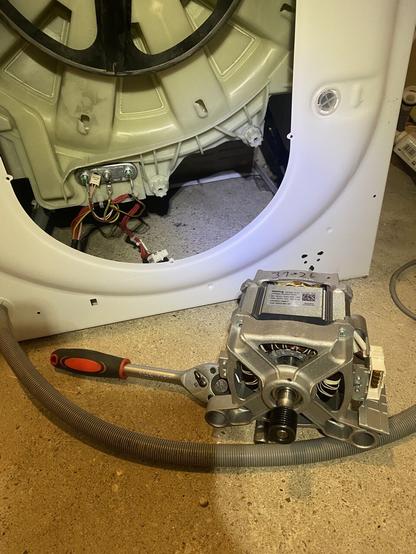 Eine geöffnete Waschmaschine. Der noch einzubauende Motor steht davor und Werkzeug liegt bereit.