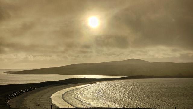 Hazy golden sunlight above the curve of a beach