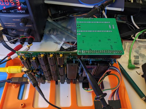 zx81+38 mainboard standing on end in case, oscilloscope probes attached, IO board plugged in, and bench power supply in the background.