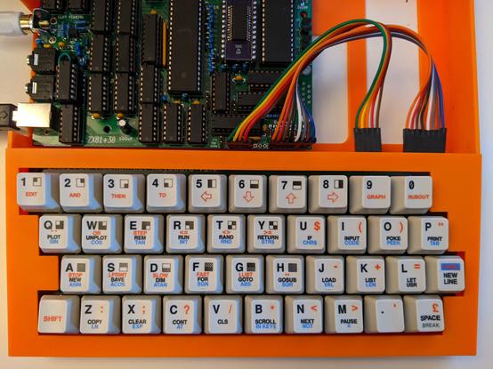 zx81+38 in orange 3D printed case, no cover over the mainboard, custom keycaps installed on the mechanical keyboard.