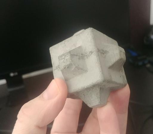 Cubípodo (como un exaedro con protuberancias en los centros de las caras) de unos 4 cm de lado, fabricado con mortero. Es una réplica a pequeña escala de unos bloques de hormigón que se emplean para construir diques en ingeniería portuaria.