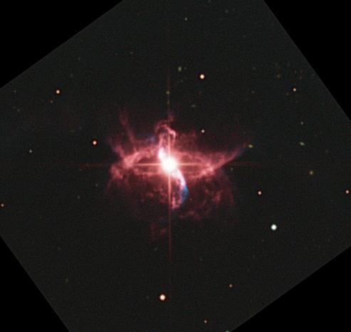 Picture showing a nebula formed by two stars. The only star visible is the bright red giant. The nebula has the shape of a lawn sprinkler shooting out water, or perhaps a ballerina spinning with her arms and legs slightly bent vertically.
This picture was taken with a .6m/24" diameter telescope, and includes H-alpha and OIII narrowband data.  The H-alpha data adds delicate wisps that extend out from the center. The OIII data adds blue jets that are appearing to go up and left, and down and right, slightly bent back to the center axis further away.
Data courtesy of iTelescope.net