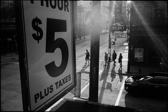 Rays of light shine in from the street illuminating pedestrians at a Vancouver intersection