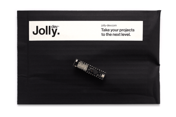 The Jolly Module printed circuit board, sat atop the packaging in which it is delivered, seen from the top on a white background.