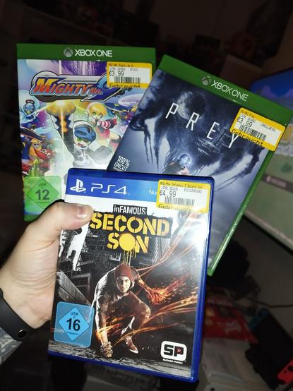 Sven hält auf diesem Bild die Drei Videospiele Mighty Number 9, Prey und Infamous Second Son in der Hand