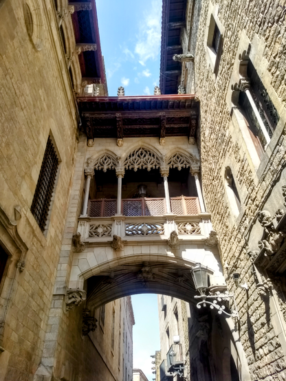 An ornate enclosed bridge connecting two buildings about 20' off the ground in the Gothic Quarter in Barcelona.