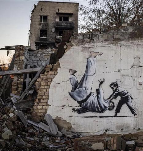 Crumbled building in Kyiv with poor small boy judo throwing an ‘adult’ (Putin)