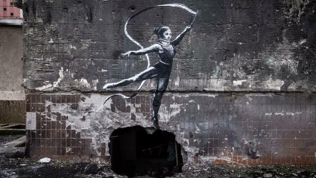 Ribbon gymnast performs on top of a hole blown into a building wall