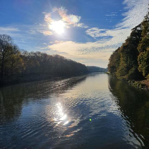 Elsterflutbett Leipzig, leicht bewölkt, die Sonne schimmert im Wasser
