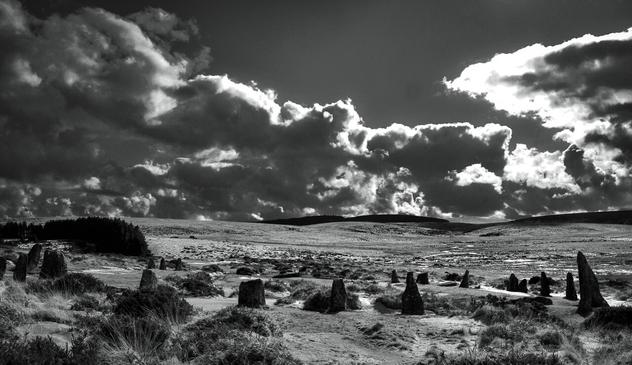 Black & White image of stone circle on moor with striking clouds