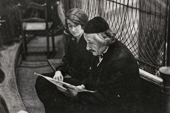 Einstein sitzend mit Kippa, neben ihm seine Sekretärin, beide schauen in ein (vermutlich) Notenpapier