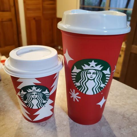Left: Starbucks coffee, short. The cup is red and has white Christmas trees along with the Starbucks logo on it. Right: Free Starbucks Reusable Red Cup. It is Red with white stars and snowflakes on it along with the Starbucks logo.