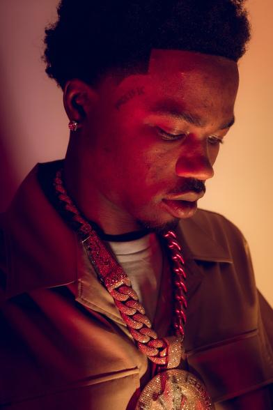 Portrait of rapper Roddy Ricch wearing a beige suit and thick necklace chain.