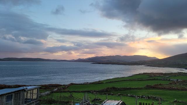 Sunrise with orange and grey clouds over the bay. Zoomed out a bit. Lilac clouds at the end of the bay.