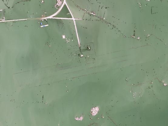 Airport at the peak of flooding, with the strip & surroundings almost  completely submerged, with the exception of an access road and a few clusters of buildings.