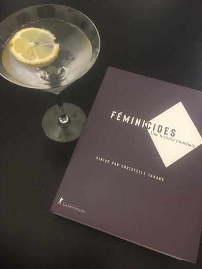 Le livre “Féminicides: une histoire mondiale” à côté d’un verre de martini